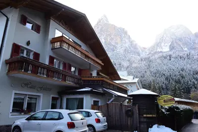 two cars parked in front of a building with mountains at Haus Fulterer in Siusi