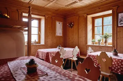 a dining room with two tables and two windows at Rifugio Malga Ra Stua in Cortina dʼAmpezzo