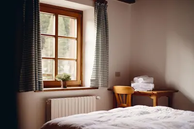 a bedroom with a bed and a window and a table at Rifugio Malga Ra Stua in Cortina dʼAmpezzo