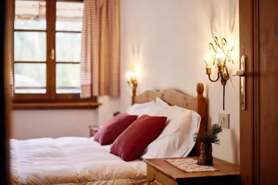 a bedroom with a bed with white sheets and red pillows at Rifugio Malga Ra Stua in Cortina dʼAmpezzo