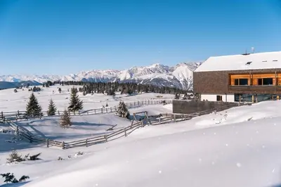 a building in the snow with mountains in the background at Starkenfeldhütte in Rodengo