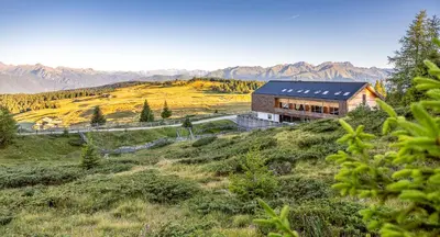 a house on a hill with mountains in the background at Starkenfeldhütte in Rodengo
