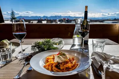 a plate of pasta on a table with glasses of wine at Starkenfeldhütte in Rodengo