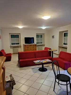 a living room with a red couch and a table at Villa San Carlo in Pozza di Fassa