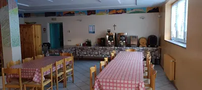 a dining room with two tables and chairs and a kitchen at Villa San Carlo in Pozza di Fassa