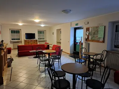 a living room with tables and chairs and a couch at Villa San Carlo in Pozza di Fassa