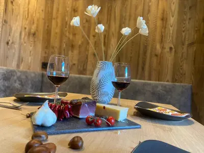a table with two glasses of wine and cheese at Villa Dolomiti in Ortisei