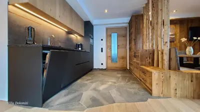 a kitchen with black appliances and wooden walls at Villa Dolomiti in Ortisei