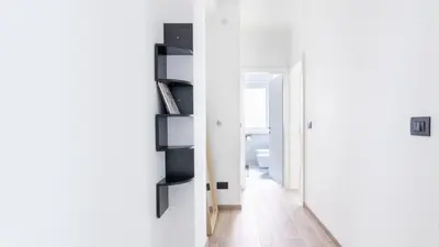 a hallway with white walls and a white door with a room at Cloudberry Home in Merano
