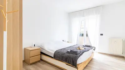 a white bedroom with a bed and a window at Cloudberry Home in Merano