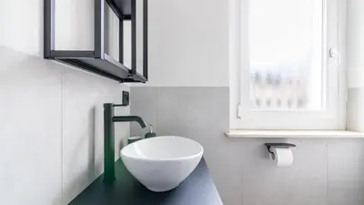 a bathroom with a white bowl sink and a window at Cloudberry Home in Merano