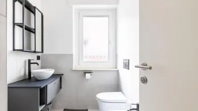 a bathroom with a toilet and a sink and a window at Cloudberry Home in Merano