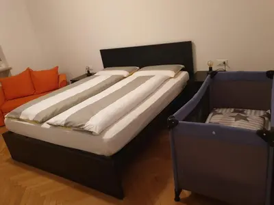 a bedroom with a large bed and an orange couch at Appartamento del CONTE a Merano, con piscina, leggere attentamente le info o chiamare direttamente l'host! in Merano