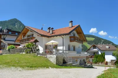 a house on a hill with mountains in the background at Apartments Ciasa Costisela in San Vigilio Di Marebbe
