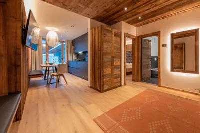 a kitchen and living room with wooden walls and wooden floors at Apartments Ciasa Costisela in San Vigilio Di Marebbe