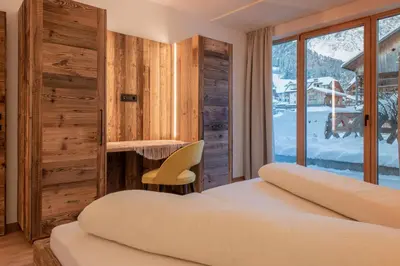 a bedroom with two beds and a desk and a window at Apartments Ciasa Costisela in San Vigilio Di Marebbe