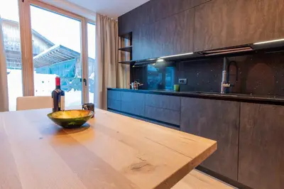 a kitchen with a wooden table with a bottle of wine at Apartments Ciasa Costisela in San Vigilio Di Marebbe