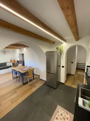 a kitchen and dining room with a table and a refrigerator at Appartamento Gioia di Bosco in Carano