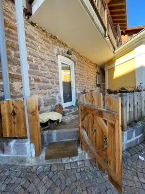 a house with wooden doors and a brick wall at Appartamento Gioia di Bosco in Carano
