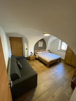 a living room with a bed and a couch at Appartamento Gioia di Bosco in Carano
