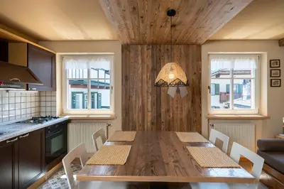 a kitchen with a wooden table with chairs and windows at Ciasa Buro - Zen in Moena