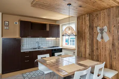 a kitchen with a table with white chairs in it at Ciasa Buro - Zen in Moena