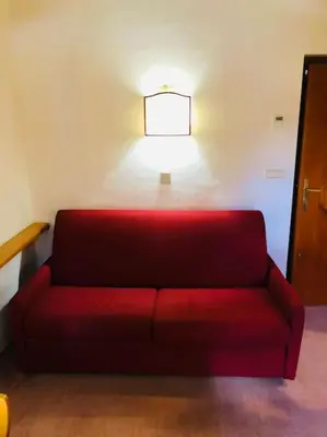 a red couch sitting in a room with a lamp at loft panorama Tre cime Dobbiaco Cortina in Dobbiaco