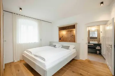 a white bedroom with a white bed and a sink at Karcher-Hof Terlan in Terlano