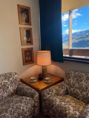 a room with two chairs and a table with a lamp at Encia's Home Dolomiti in Castello di Fiemme