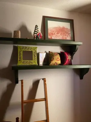 a shelf on the wall with pillows and a picture at Encia's Home Dolomiti in Castello di Fiemme