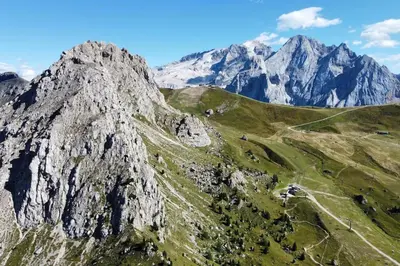 a mountain with a green field and mountains in the background at Encia's Home Dolomiti in Castello di Fiemme
