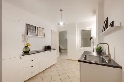 a kitchen with white cabinets and a sink at Argentieri City Loft in Bolzano