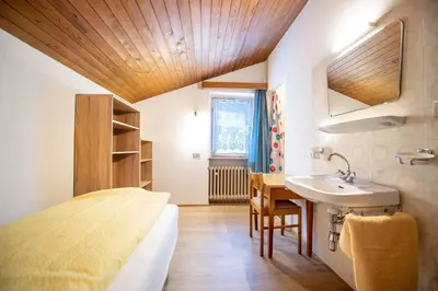 a bedroom with a bed and a sink and a table at Apartments Karl in Ortisei