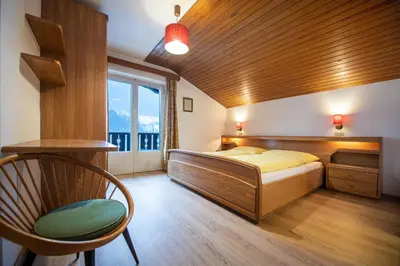 a bedroom with a bed and a chair and a window at Apartments Karl in Ortisei