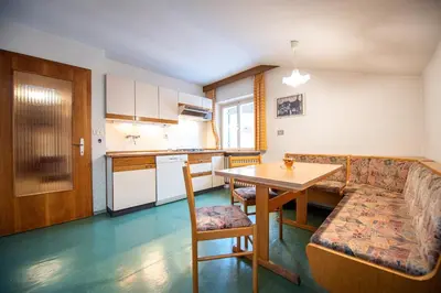 a kitchen and dining room with a table and a couch at Apartments Karl in Ortisei