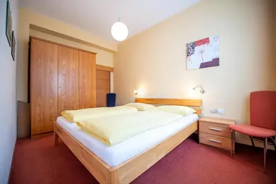 a bedroom with a large bed and a chair at Apartments Karl in Ortisei