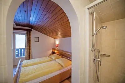a bathroom with a bed and a shower in a room at Apartments Karl in Ortisei