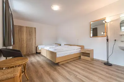 a bedroom with a bed and a table and a mirror at Central Apartments Cristlpek in Ortisei