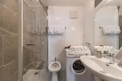 a bathroom with a washing machine and a sink at Central Apartments Cristlpek in Ortisei