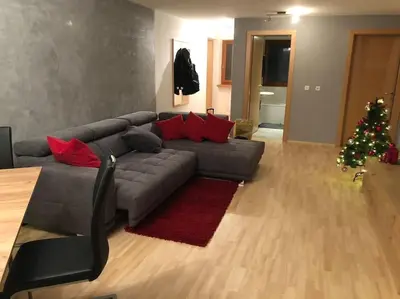 a living room with a gray couch and a christmas tree at Appartamento nuovo e comfort a Brunico Kronplatz in Brunico