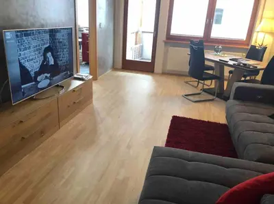 a living room with a couch and a tv and a table at Appartamento nuovo e comfort a Brunico Kronplatz in Brunico