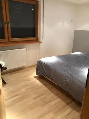 a bedroom with a bed and a wooden floor at Appartamento nuovo e comfort a Brunico Kronplatz in Brunico