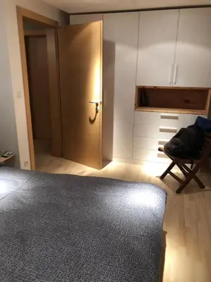 a room with a door and a chair and a closet at Appartamento nuovo e comfort a Brunico Kronplatz in Brunico