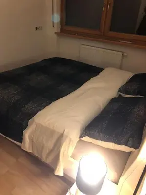 a bed in a room with a lamp on the floor at Appartamento nuovo e comfort a Brunico Kronplatz in Brunico