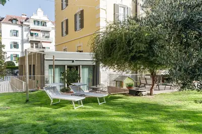 a yard with two chairs and a tree and buildings at Villa Stubai Garden Suite in Merano
