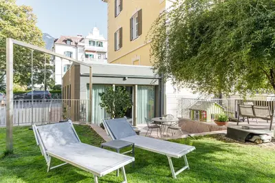 a patio with two chairs and a table in a yard at Villa Stubai Garden Suite in Merano