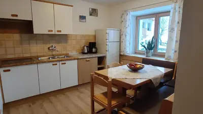 a kitchen with white cabinets and a table and a window at Villa Erica in Badia