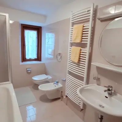 a white bathroom with a toilet and a sink at Villa Erica in Badia