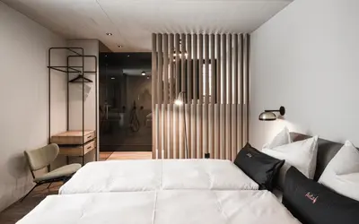 a bedroom with a white bed and a chair at Avita Loft by Avita suites to relax in Santa Cristina in Val Gardena