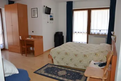 a bedroom with a bed and a table and a desk at Garní Ladinia in Pescul